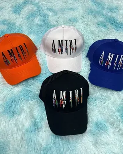 Five baseball caps on a pale blue fur surface, in orange, white, blue and black