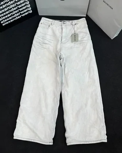A pair of light-wash wide-leg jeans laid flat with the paper tag still attached